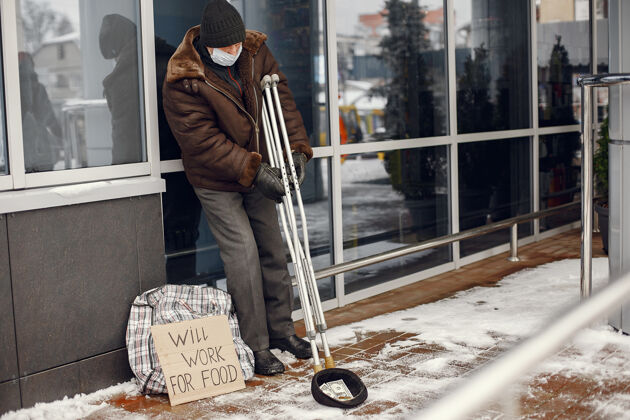 悲伤无家可归的人站在大楼附近冷城市不快乐