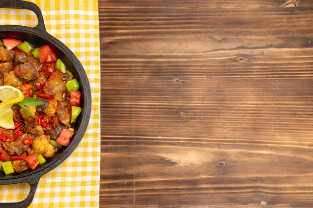 烹饪在棕色的木桌上 用锅里的肉和切好的甜椒做的蔬菜大餐俯视图沙拉里面一餐