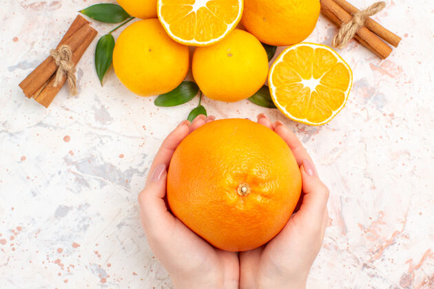 顶部顶视图新鲜的柑桔肉桂棒橙色在女人的手上明亮的孤立的表面肉桂棒维生素