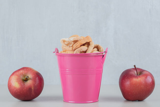 苹果收获一个粉红色的桶里装满了干苹果和两个新鲜苹果甜饮食吃