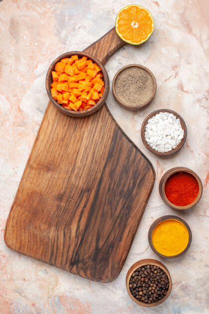 切胡萝卜顶视图切割胡萝卜在碗里在砧板上不同的香料在小碗裸体表面午餐烹饪切