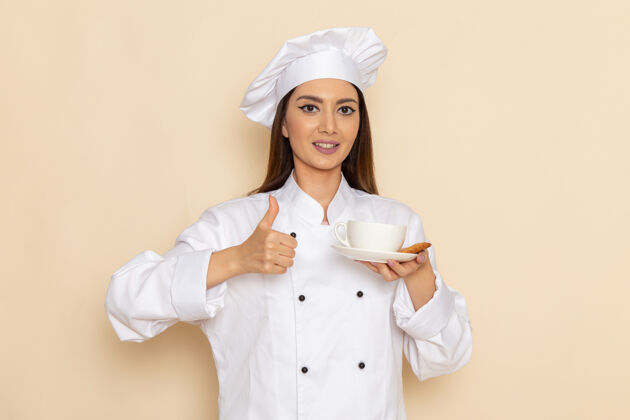 微笑身穿白色厨师服的年轻女厨师正拿着一杯咖啡 微笑着站在白墙上杯子人年轻