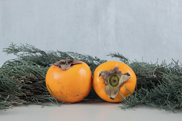 水果两个新鲜的柿子放在圣诞树枝上圆形美味可食用