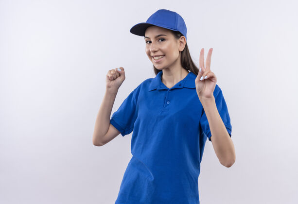 胜利身穿蓝色制服 握紧帽子 握紧拳头 展示胜利标志的年轻送货女孩交付拳头制服