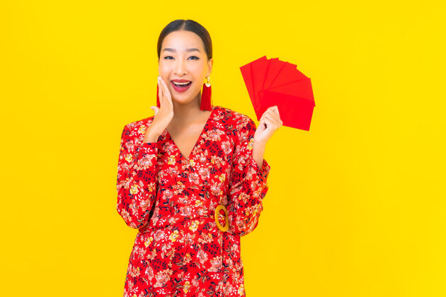 风景在黄色的墙上画一幅美丽的亚洲年轻女子拿着红包服饰春天中国人