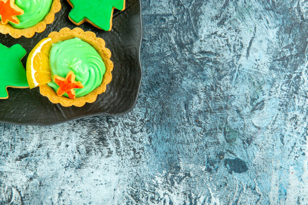 奶油上半部分查看绿色糕点奶油小馅饼圣诞树饼干黑色盘子上的灰色表面与复制空间糕点半年龄