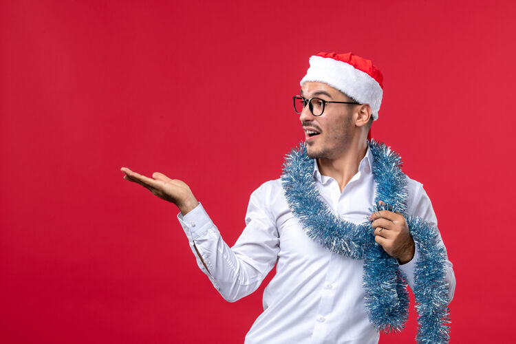 庆祝正面图普通男性在红墙庆祝新年人类节日圣诞节姿势表演帅哥