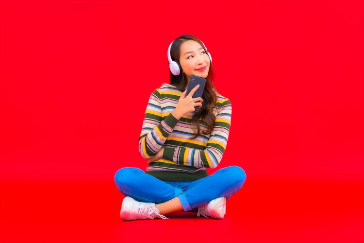 女性肖像美丽的亚洲年轻女子使用智能手机和耳机听音乐亚洲人女士室内