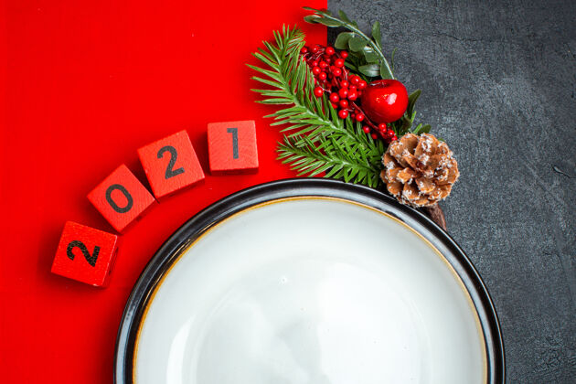 圣诞新年背景与餐盘装饰配件杉木枝和数字在一个黑色的桌子上红色餐巾水桶餐巾餐盘