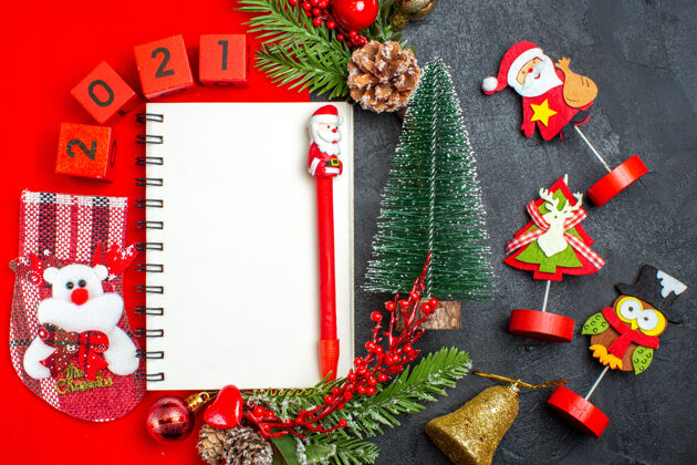 书签俯视图螺旋笔记本装饰配件杉木枝xsmas袜子号码在一个红色餐巾和圣诞树在黑暗的背景冬青袜子树枝