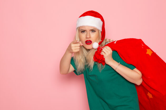 携带正面图：年轻女性提着红包 粉色墙壁上有礼物模型圣诞老人新年照片假日圣诞老人美丽肖像