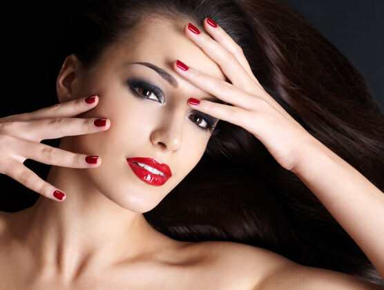 美甲长着棕色直发和红指甲的漂亮女人躺在黑暗的墙上棕色眼睛黑发姿势