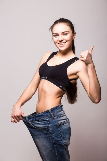 牛仔裤年轻女子穿了一条旧牛仔裤来显示她的减肥效果护理测量成功
