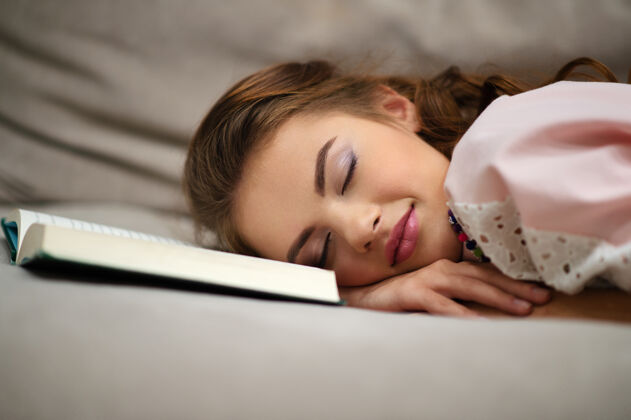 学生疲惫的年轻女子躺在沙发上拿着一本书在家小睡女人教育床