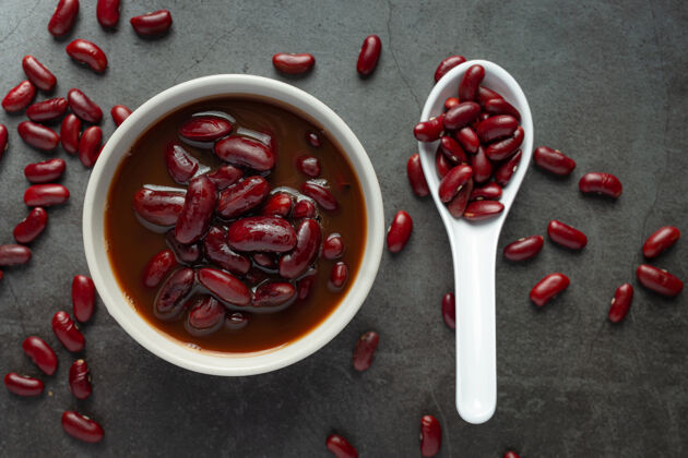 食谱红豆煮在白碗里 红豆籽放在勺子里 放在黑暗的地板上有机食品必要的