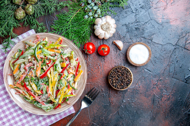 餐顶视图蔬菜沙拉在盘子上在桌布叉子上盐和黑胡椒大蒜西红柿在深红色的桌子上餐厅西红柿蔬菜沙拉