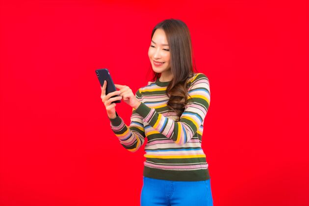 亚洲人在红墙上画一幅美丽的亚洲年轻女子手持智能手机的画像成人商务年轻人