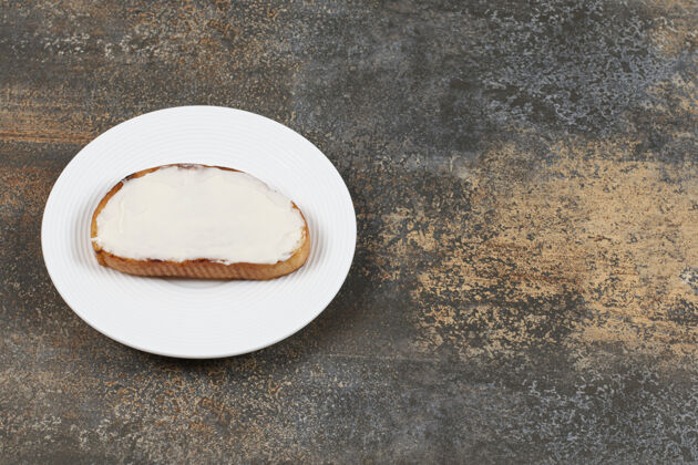 好吃的在白色盘子上放一片带酸奶油的烤面包片酸的切片正餐