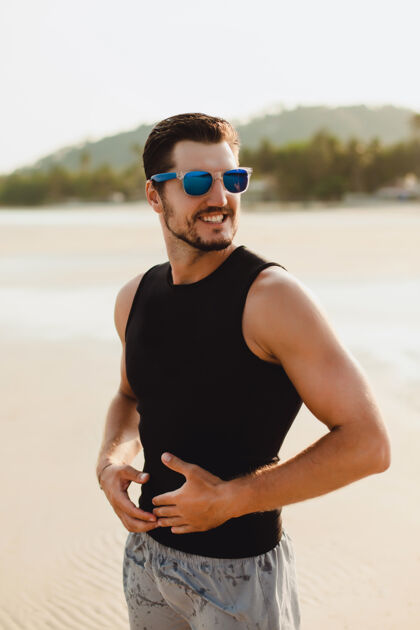 身体帅哥户外写真 在沙滩上穿着黑色无袖t恤和短裤海边温暖的阳光天气冲浪板肌肉运动男人