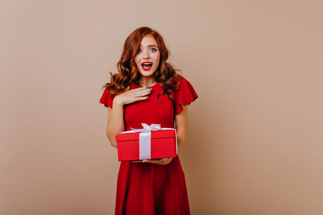 圣诞节一个穿着红裙子的女人拿着礼物 一个漂亮的姜汁女孩在庆祝生日红发玩漂亮