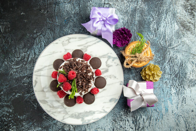 营养品俯视图：椭圆形盘子上的巧克力芝士蛋糕 灰色表面上的圣诞礼物菜肴美食顶部