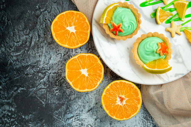 水果顶视图小馅饼与绿色糕点奶油和柠檬片在盘子上米色披肩切橘子在黑暗的桌子上复制的地方多汁小可食用水果