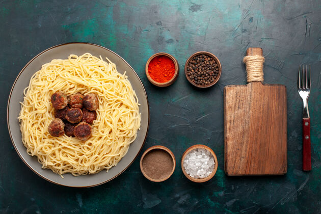 饭在深蓝色的桌子上俯瞰煮熟的意大利面食和肉丸和调味品食物烹饪午餐