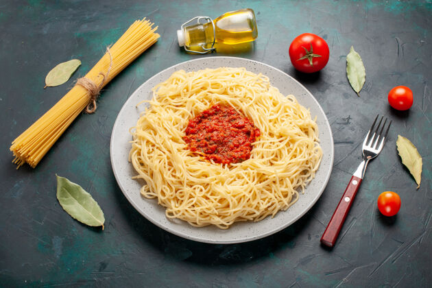 顶部在深蓝色的桌子上俯瞰着意大利面和番茄肉末肉配料桌子