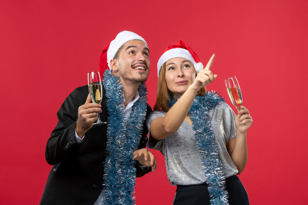 肖像正面图年轻夫妇在红墙上庆祝新年爱圣诞派对饮料微笑圣诞成人