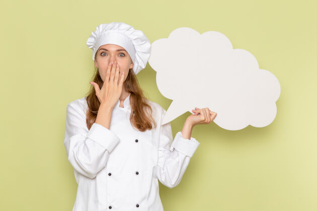 烹饪身穿白色厨师服的女厨师正对着绿色墙上举着巨大的白色标牌微笑巨大用餐