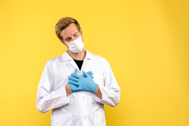 医生正面图黄色背景上的男医生感到疲倦大流行的冠状病毒-健康病毒服装男性冠状病毒