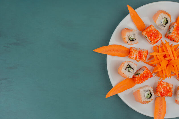 海鲜把寿司和胡萝卜片放在白色盘子里鱼费城加州