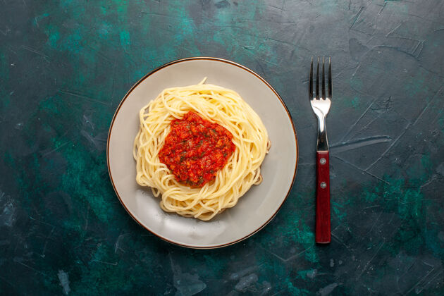 食物在深蓝色的桌子上俯瞰着意大利面和肉末和番茄酱西红柿生的肉末