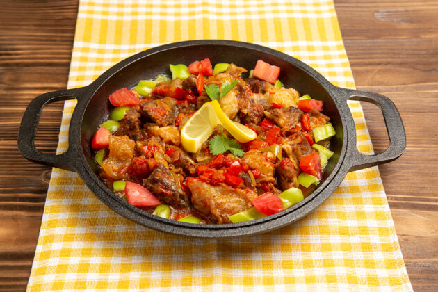 菜肴正面图棕色桌子上的熟肉蔬菜餐和切成片的甜椒胡椒粉食物前面