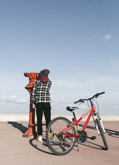 自行车骑自行车的男孩透过望远镜看户外爱好垂直年轻