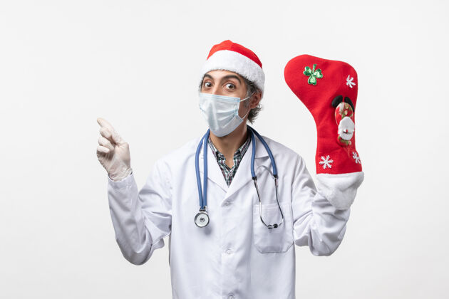 医生正面图白色墙壁上戴着大节日袜子的男医生可维圣诞病毒医院护士听诊器