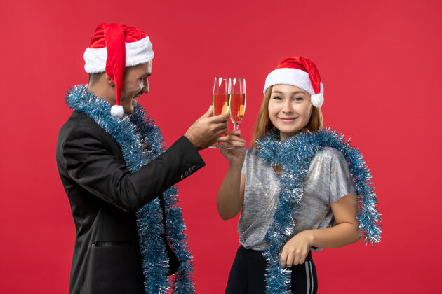 圣诞节正面图：年轻夫妇在红墙上庆祝新年颜色爱圣诞节微笑美丽颜色