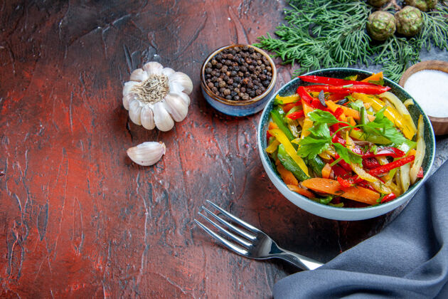 蔬菜沙拉顶视图蔬菜沙拉碗群青蓝色披肩大蒜黑胡椒叉在暗红色的桌子上美食胡椒食物