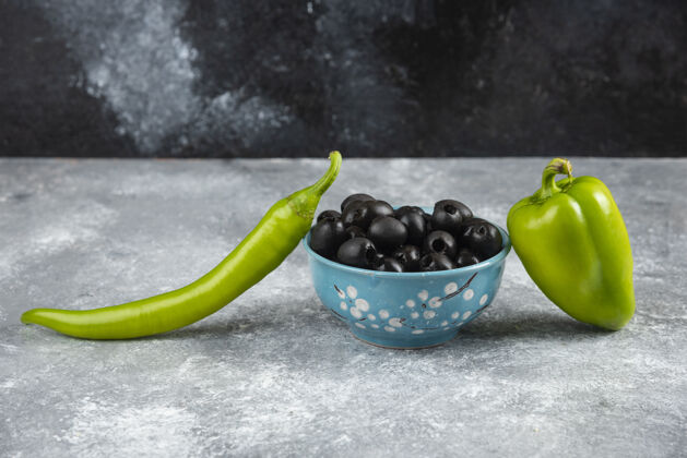 成熟黑橄榄和胡椒放在大理石桌上铃铛碗辣椒