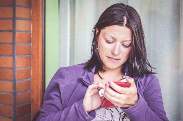 现代穿着紫色夹克的黑发女人在用智能手机年轻使用吸引力