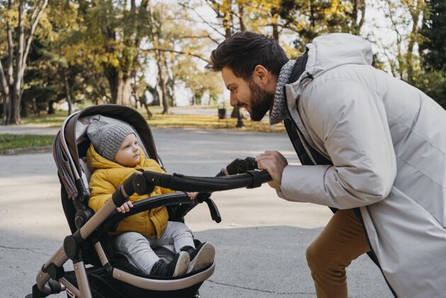 户外快乐的男人和他的孩子在外面的婴儿车在一起爱男人