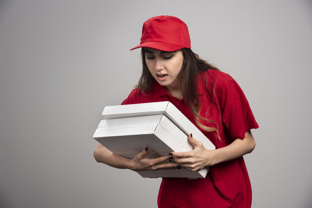 食物女信使紧握着灰色墙上的比萨饼盒服务表情女人