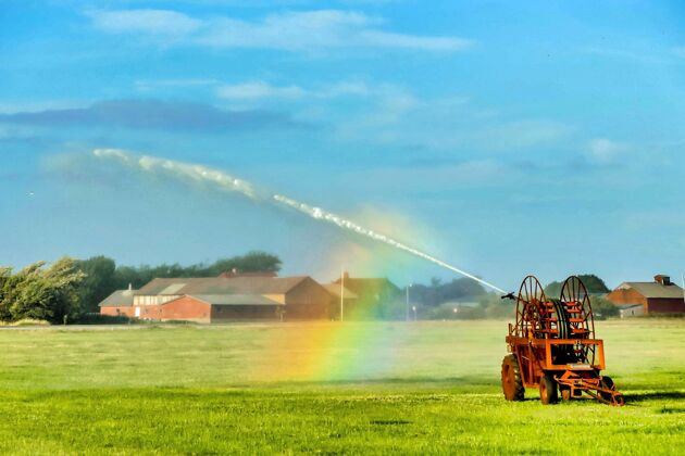 湿润美丽的彩虹从喷水器形成的镜头绿色洒水农村