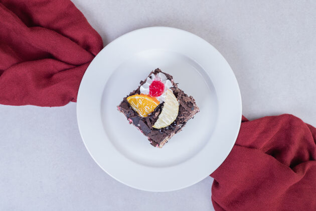 盘子用红桌布把巧克力蛋糕片放在白色盘子里巧克力顶部视图桌布