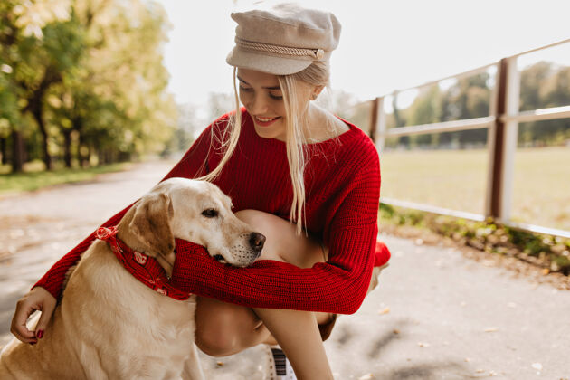 女人快乐的女人在秋天的公园里温柔地牵着她的狗可爱的金发女孩在户外和宠物玩得很开心时尚金发柔软