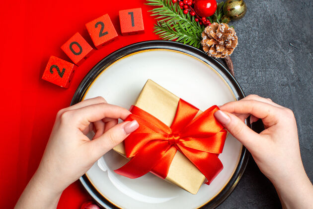 潘趣酒新年背景与礼物在餐盘装饰配件杉木枝和数字在一个黑色的桌子上红色餐巾树枝冷杉号码