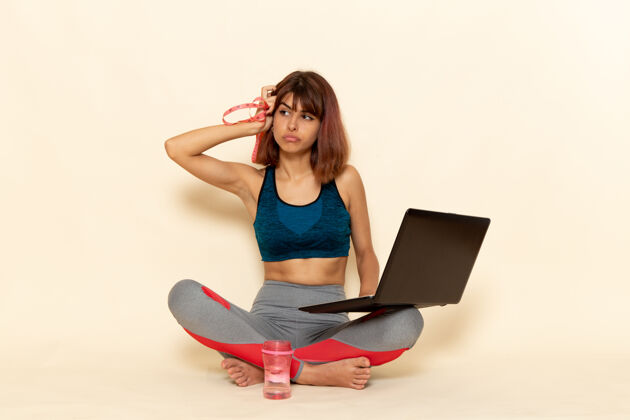 漂亮年轻女性穿着蓝色衬衫 身体健康 在浅白墙上使用笔记本电脑的前视图健康年轻身体