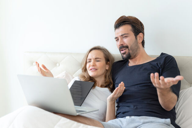 足球英俊的丈夫和美丽的妻子在卧室里用笔记本电脑看电影 感觉很浪漫生活科技妻子