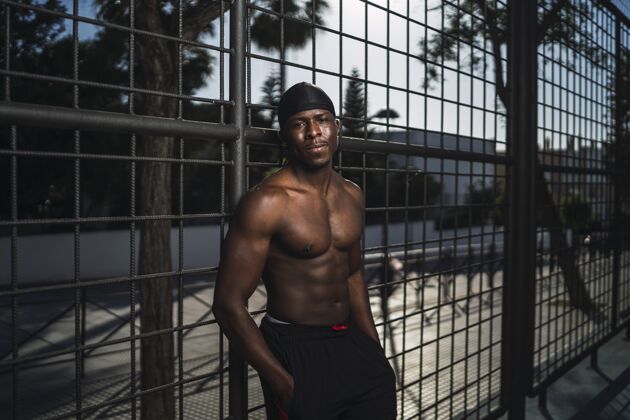男子一个半裸的非洲裔美国男性靠在篱笆上的浅焦镜头健康平衡瘦