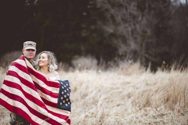 国家美国士兵和他微笑的妻子裹着美国国旗包裹织物人